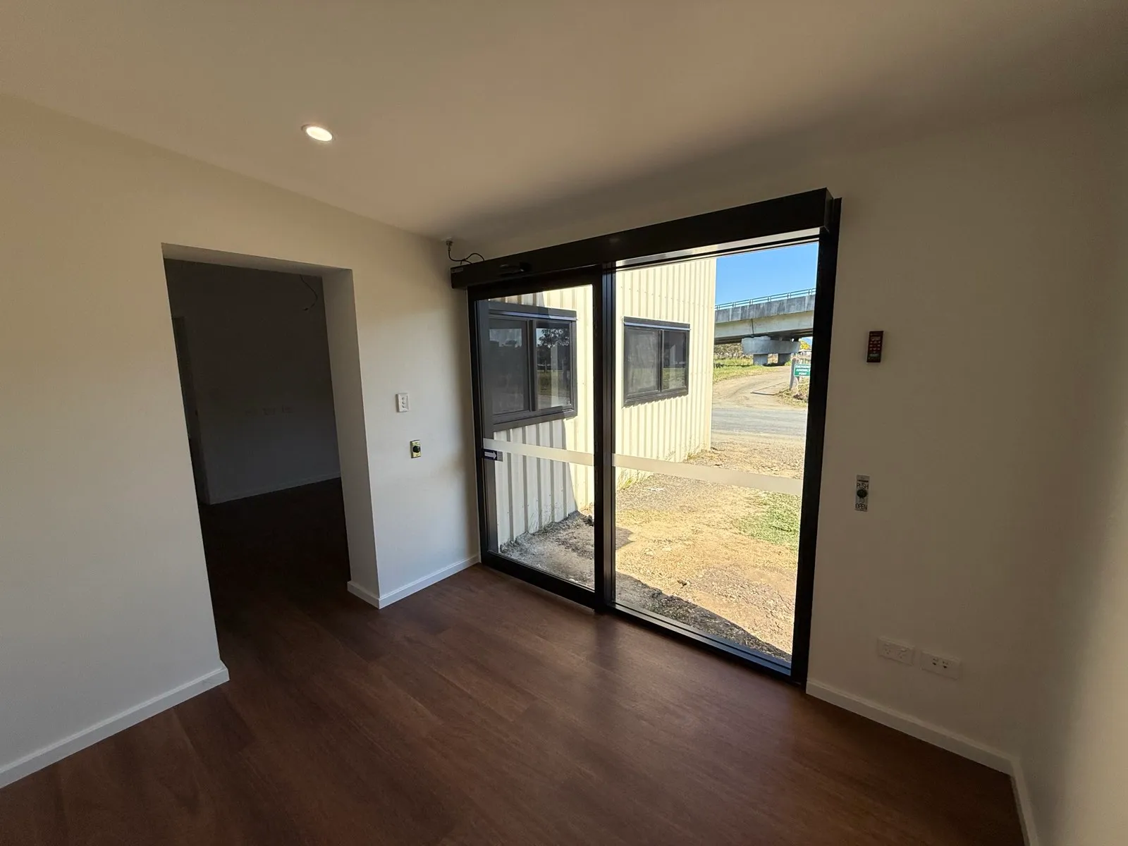 Automatic sliding glass entry doors at the works depot office, looking out to the Colorbond shed and the highway overpass, Macksville